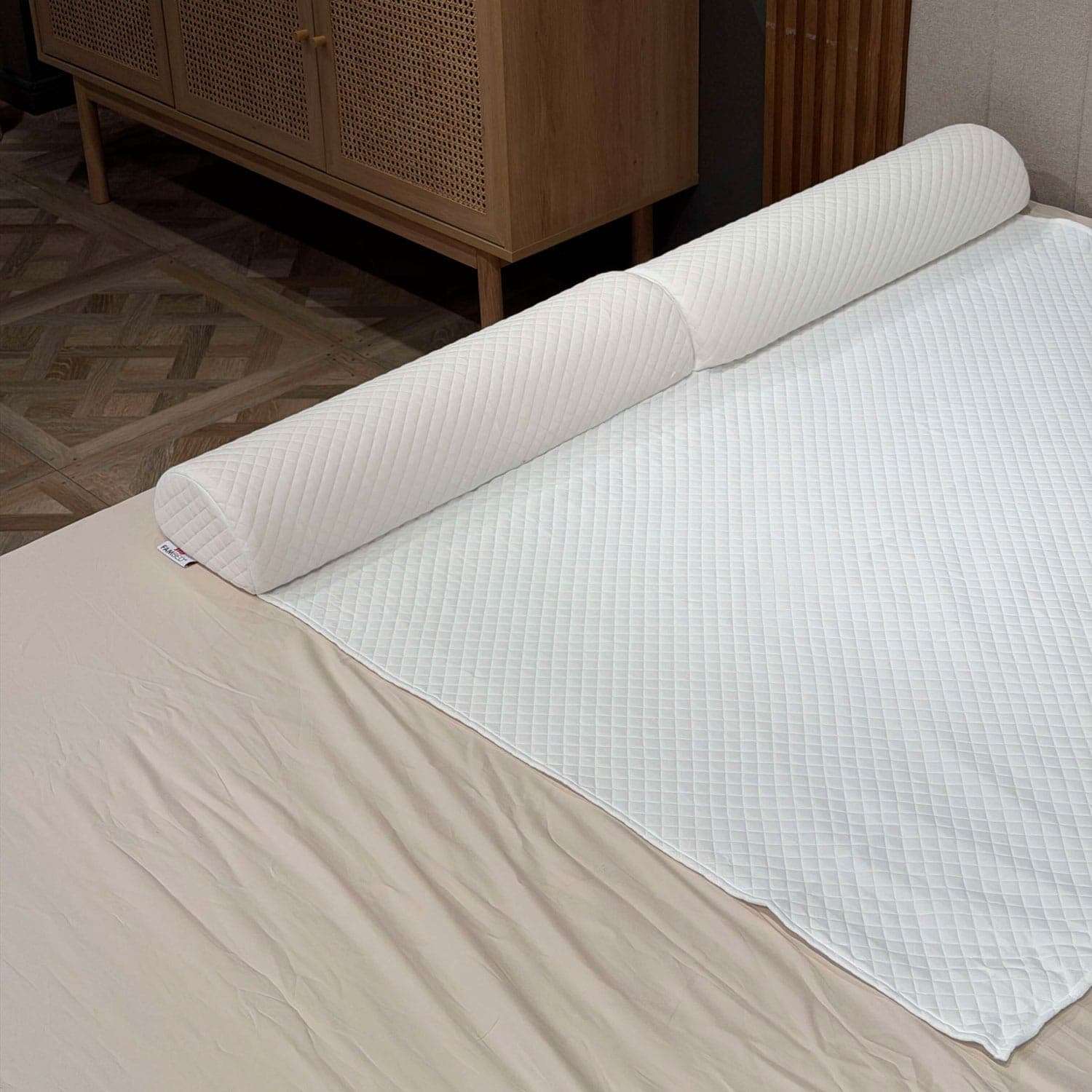 Barreira de cama acolchoada em espuma, colocada sob a capa branca do sobrecolchão ao longo da lateral da cama