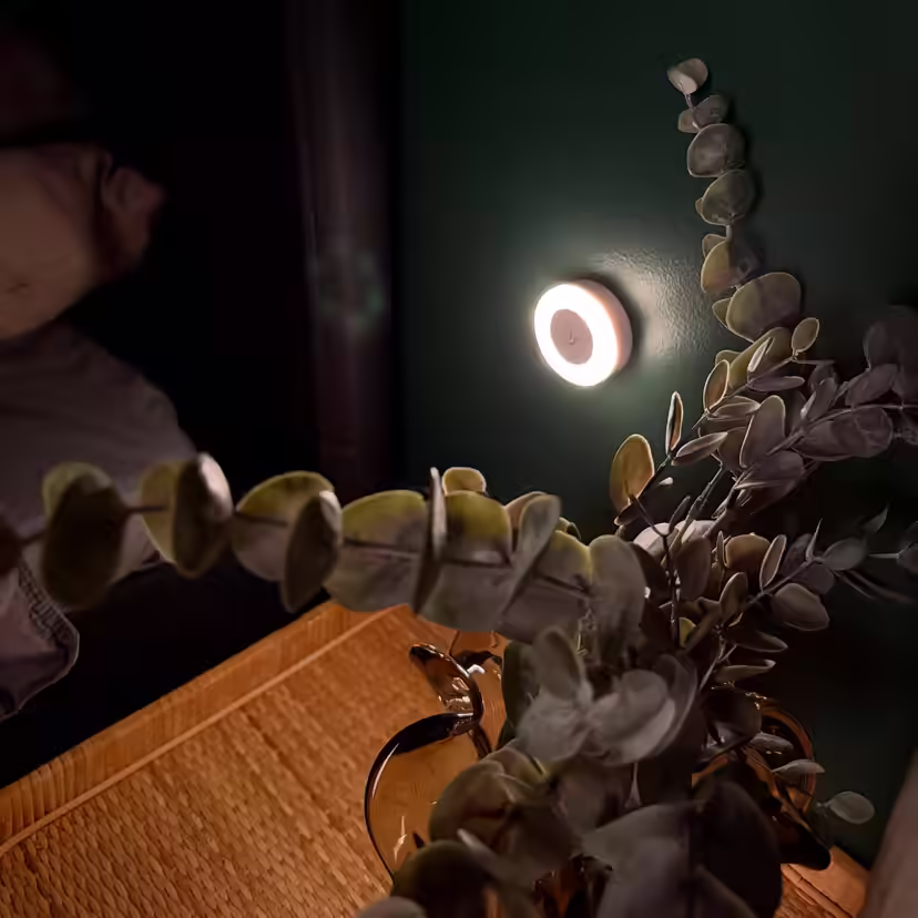 Candeeiro de amamentação redondo que ilumina suavemente a parede junto à cama durante a noite