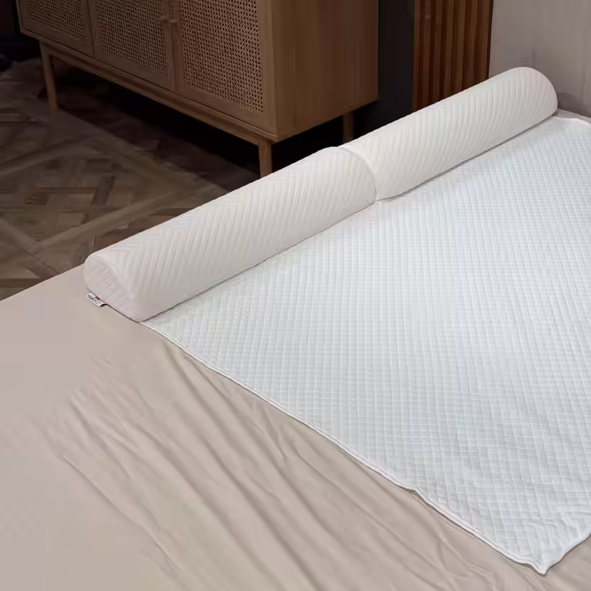 Barreira de cama acolchoada em espuma, colocada sob a capa branca do sobrecolchão ao longo da lateral da cama